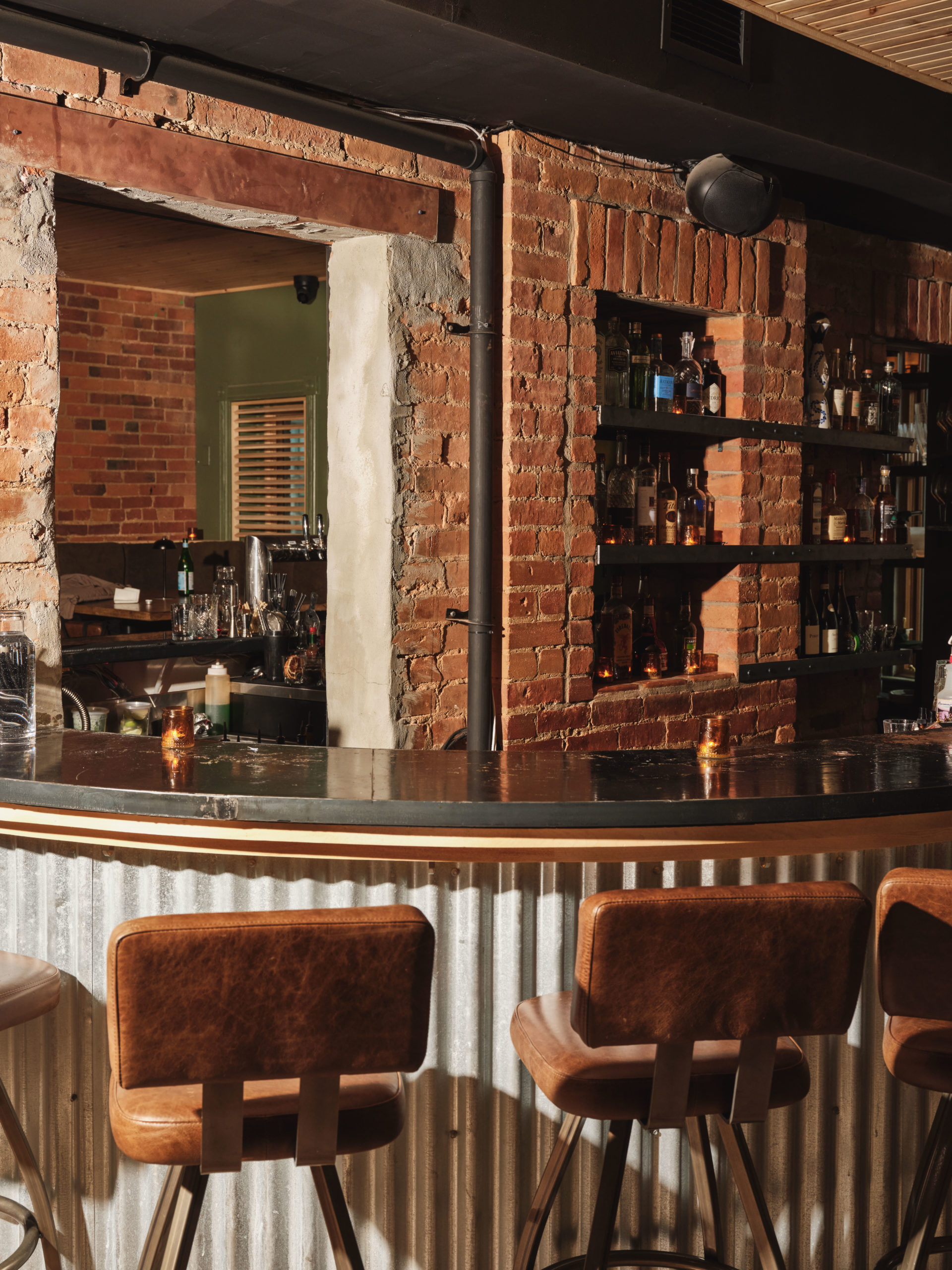 Barstools line a horseshoe-shaped bar in a space with exposed brick walls