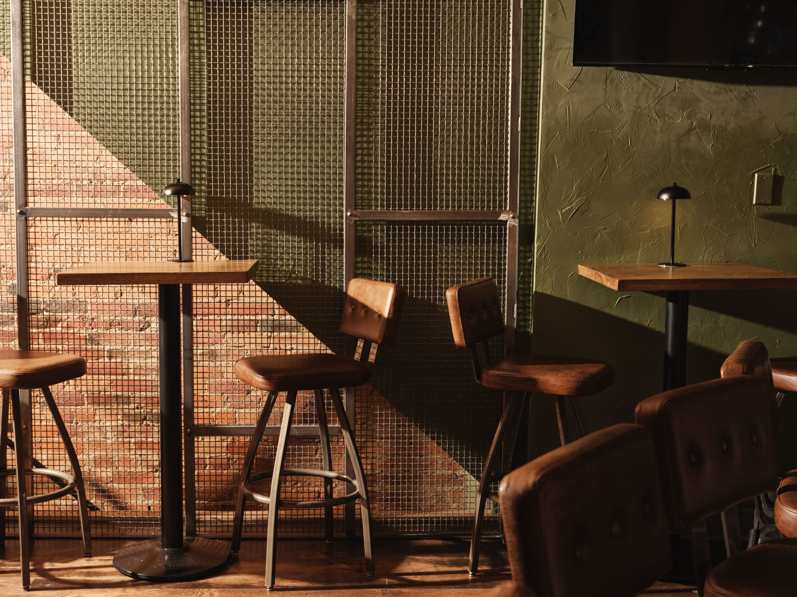 Two-top tables and barstools in a dimly lit restaurant